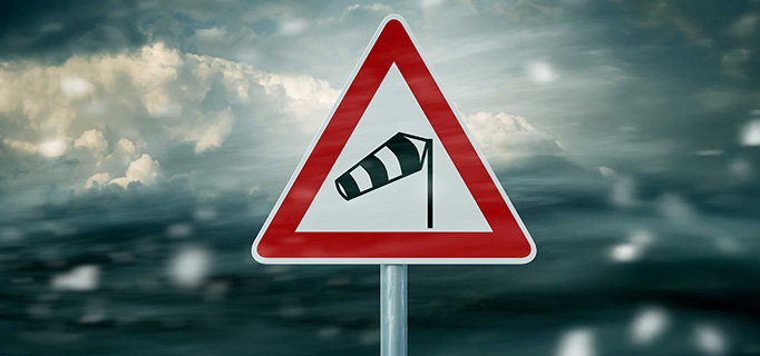 Een bord die waarschuwt voor harde wind als symbool voor stormschade.